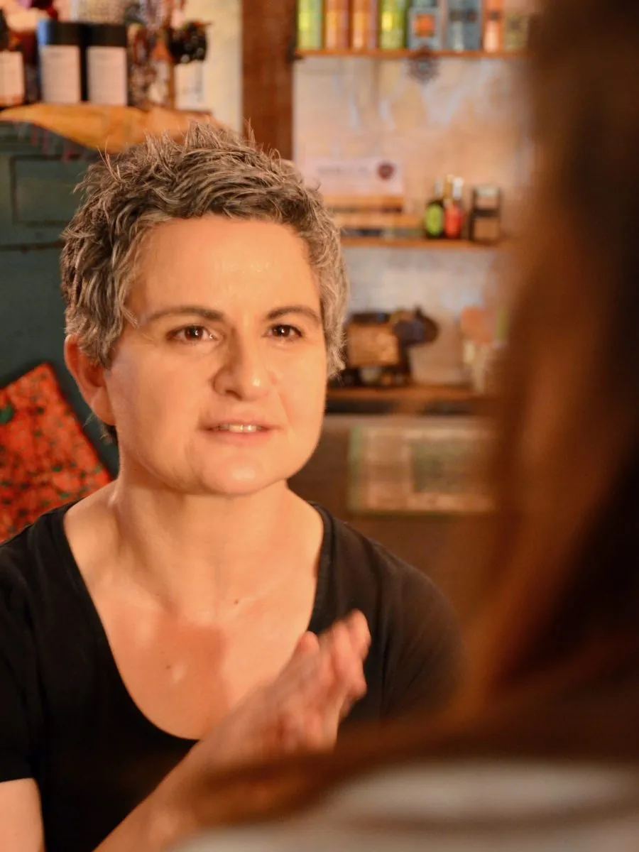 Marye in the Maiaveda apothecary, shelves of oils behind her